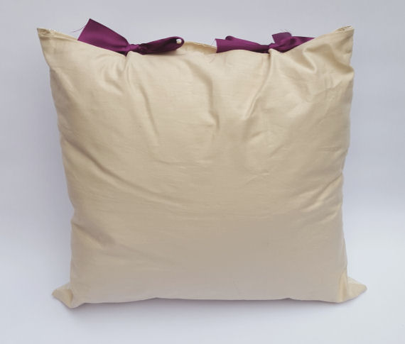 A Handmade Oatmeal like Beige Cushion with a Purple and Green Butterfly Design and Purple Bows