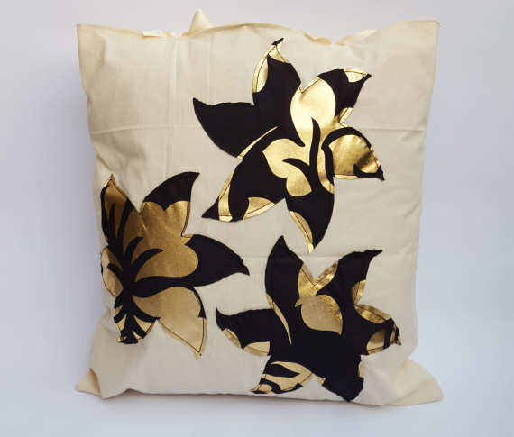 A Handmade Natural Calico Cushion with Gold and Black Floral Stencil Design with Ribbon Bows