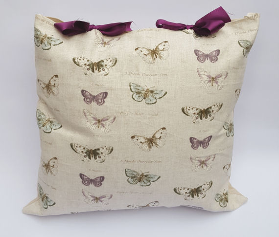 A Handmade Oatmeal like Beige Cushion with a Purple and Green Butterfly Design and Purple Bows